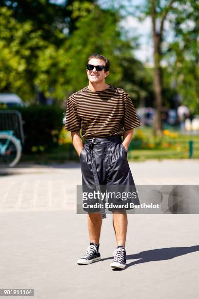 Carlo Sestini wears a black and yellow striped top, black long shorts, sneakers shoes, outside Cerruti, during Paris Fashion Week - Menswear...