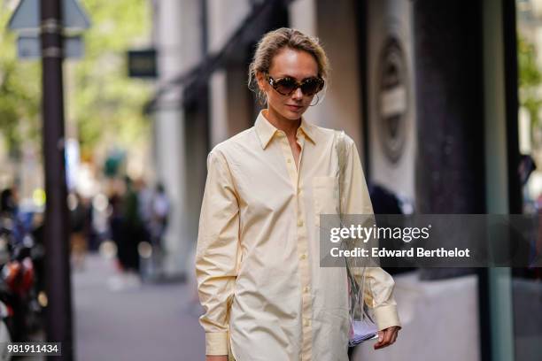 Olga Karput wears sunglasses, a beige shirt, shorts, yellow sandals, outside CDG Comme des Garcons, during Paris Fashion Week - Menswear...