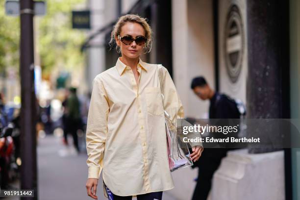 Olga Karput wears sunglasses, a beige shirt, shorts, yellow sandals, outside CDG Comme des Garcons, during Paris Fashion Week - Menswear...