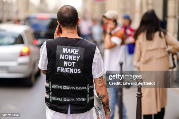 Guest wears a jacket with the printed quote "make money not friends", outside CDG Comme des Garcons, during Paris Fashion Week - Menswear...