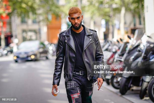 Guest wears a black leather jacket, flared colored pants, outside CDG Comme des Garcons, during Paris Fashion Week - Menswear Spring-Summer 2019, on...