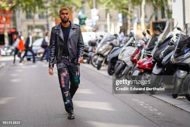 Guest wears a black leather jacket, flared colored pants, outside CDG Comme des Garcons, during Paris Fashion Week - Menswear Spring-Summer 2019, on...