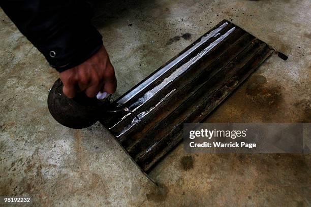 Palestinian worker pours melted recycled-metal into a mould at a car-battery workshop March 29, 2010 in Jabaliya, Gaza Strip. Workers at the...