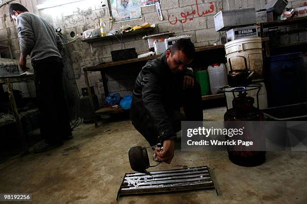 Palestinian worker, Shaher al-Helou pours melted recycled-metal into a mould at a car-battery workshop March 29, 2010 in Jabaliya, Gaza Strip....