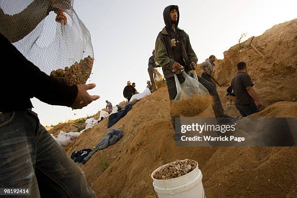 Palestinian workers sieve through dirt for stone, close to the Israeli border March 22, 2010 in Beit Lahiya, Gaza Strip. In the last few months the...