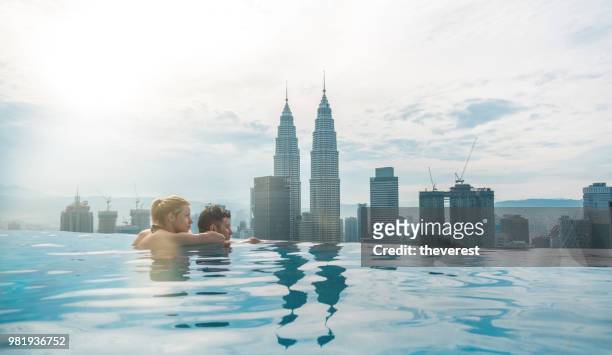 couple in the swimming pool with the stunning view of kuala lumpur - rooftop pool imagens e fotografias de stock