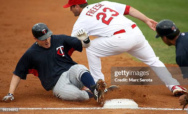 Third baseman David Freese of the St. Louis Cardinals cannot make the tag on Brendan Harris of the Minnesota Twins at Roger Dean Stadium on March 29,...