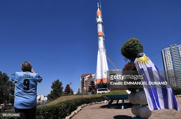 Man wearing a shirt of Uruguay's forward Luis Suarez takes a photo of the Russian Soyuz booster rocket displayed at the entrance of the Samara Space...