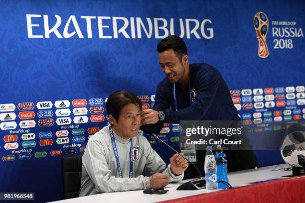 Maya Yoshida of Japan helps Akira Nishino, Manager of Japan with his earpiece in a press conference ahead of the FIFA World Cup Group H match between...