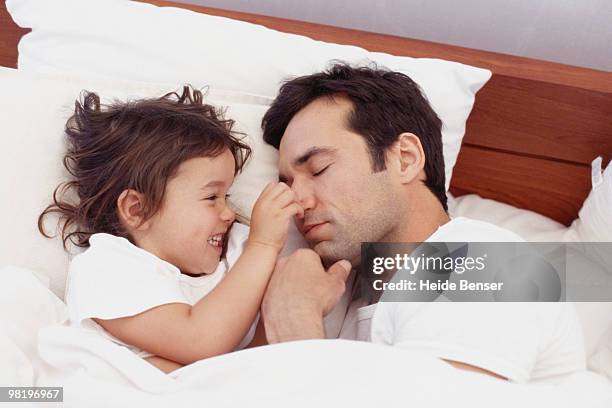 little girl pinches her sleeping father's nose - pinching nose stockfoto's en -beelden