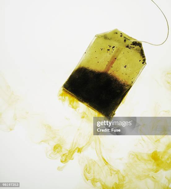 tea bag soaking in water - teebeutel stock-fotos und bilder