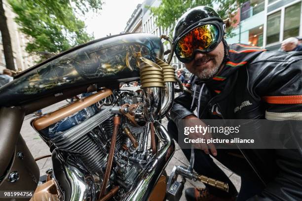 June 2018, Germany, Hamburg: Harley Davidson driver Thomas Theis kneels next to his custom bike at the Ride-In Bike Show of the Harly Days. He...