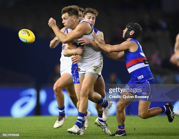 Shaun Higgins of the Kangaroos handballs whilst being tackled by Mitch Honeychurch of the Bulldogs during the round 14 AFL match between the Western...