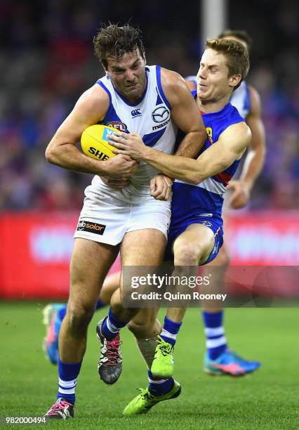 Luke McDonald of the Kangaroos is tackled by Lachie Hunter of the Bulldogs during the round 14 AFL match between the Western Bulldogs and the North...