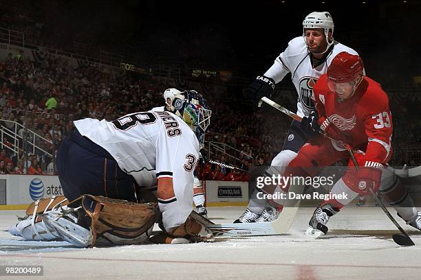 Goaltender Jeff Deslauries of the Edmonton Oilers covers the puck as teammate Ryan Whitney ties up Kris Draper of the Detroit Red Wings during an NHL...