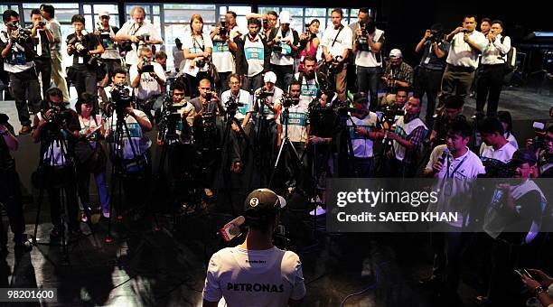 Journalists crowd around Mercedes Formula One driver Michael Schumacher of Germany as he talks outside the Kuala Lumpur Convention Centre on March...