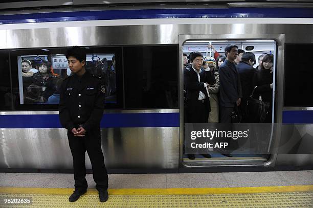 Chinese policeman stands by a door of a train at a metro station in Beijing on March 30, 2010. Beijing police said they had beefed up security in the...