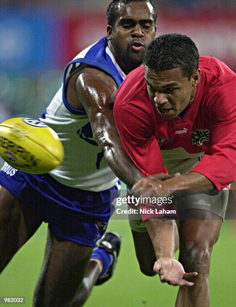 Robert Ahmat of the Swans handpasses the ball despite pressure from Byron Pickett of the Kangaroos during the round 3 AFL match between the Sydney...