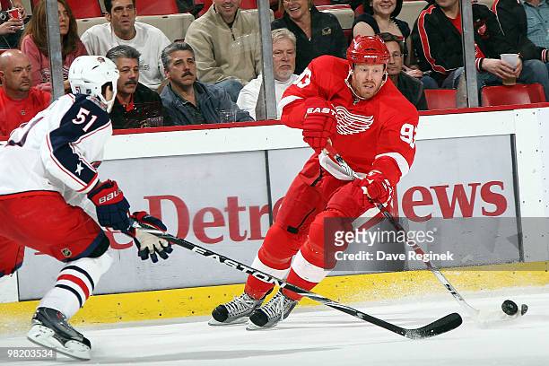 Johan Franzen of the Detroit Red Wings tries to skate with the puck around the defense of Fedor Tyutin of the Columbus Blue Jackets during an NHL...