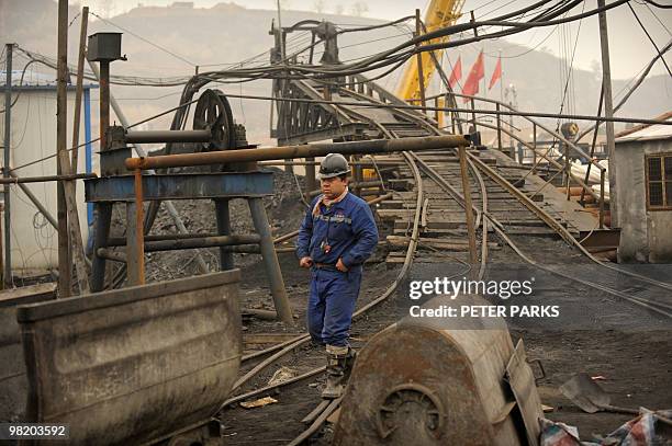 Mine worker walks through the entrance to the Wangjialing coal mine where rescuers are trying to find more than 150 workers trapped in the flooded...