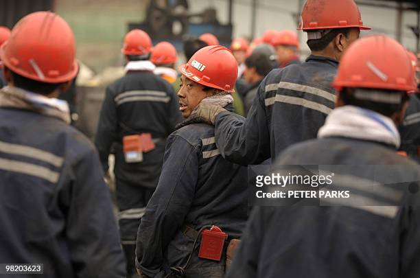 Mine workers come up from underground at the entrance to the Wangjialing coal mine where rescuers are trying to find more than 150 workers trapped in...