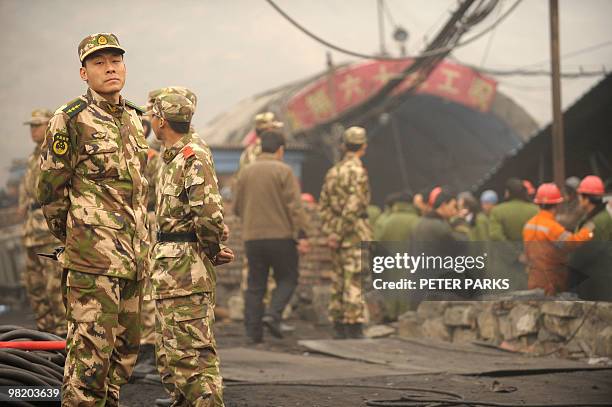 Paramilitary police stand guard at the entrance to the Wangjialing coal mine where rescuers are trying to find more than 150 workers trapped in the...