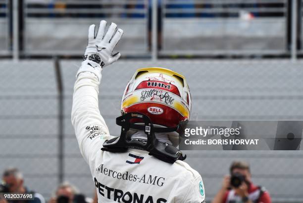 The lettering 'Still I rise' is seen on the helmet of Mercedes' British driver Lewis Hamilton as he celebrates winning the pole position after the...
