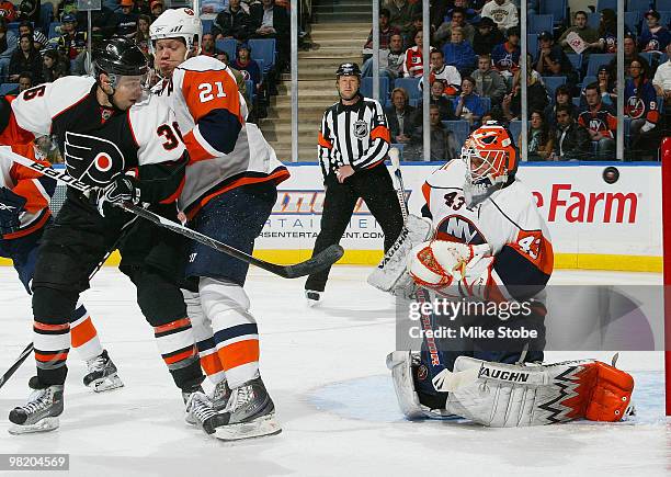 Kyle Okposo of the New York Islanders ties up Darroll Powe of the Philadelphia Flyers as goaltender Martin Biron of the Islanders makes the save on...