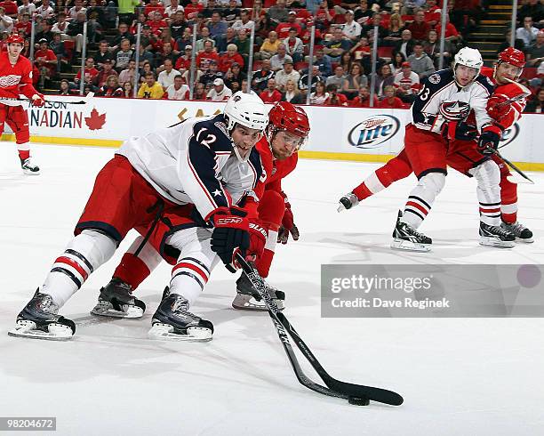 Niklas Kronwall of the Detroit Red Wings and Mike Blunden of the Columbus Blue Jackets get their sticks tied up as they battle for the loose puck...