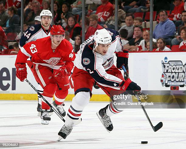 Mike Blunden of the Columbus Blue Jackets skates up ice with the puck as Darren Helm of the Detroit Red Wings trails during an NHL game at Joe Louis...
