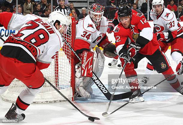 Mike Fisher of the Ottawa Senators reaches for a rebound as Jamie McBain of the Carolina Hurricanes controls the puck and Manny Legace of the...