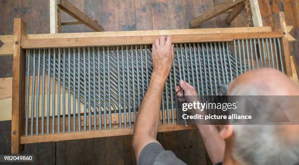 June 2018, Germany, Sieversdorf: Claudius Eckert, organ builder of the organ workshop Scheffler, repares an octavo switch of a Sauer organ from 1904....