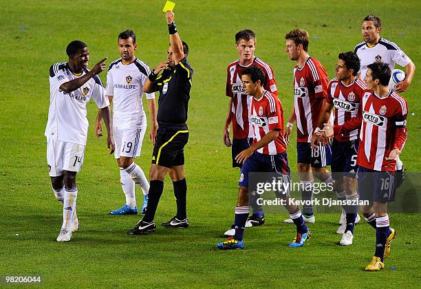 Edson Buddle of the Los Angeles Galaxy is shown the yellow card by referee Ricardo Salazar as he argues with Sacha Kljestan of Chivas USA during the...