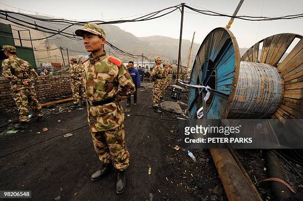 Paramilitary police stand guard at the entrance to the Wangjialing coal mine where rescuers are trying to find more than 150 workers trapped in the...