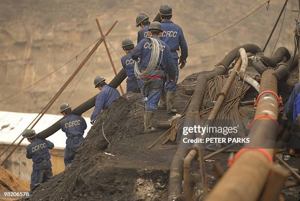 Mine workers carry pipes to the entrance to the Wangjialing coal mine where rescuers are trying to find more than 150 workers trapped in the flooded...