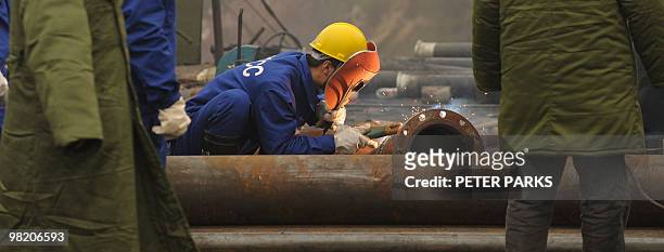 Mine worker welds a pipe at the entrance to the Wangjialing coal mine where rescuers are trying to find more than 150 workers trapped in the flooded...