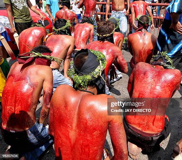 Roman Catholic devotees kneel in front on the church after wiping their flagellated backs during a ritual for Holy Week on the run up to Easter in...