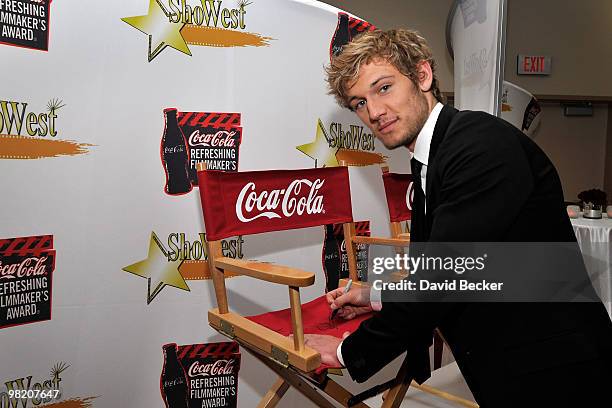 Actor Alex Pettyfer signs a director's chair for a charity auction for Coca-Cola before the ShoWest final night banquet and awards ceremony at Paris...