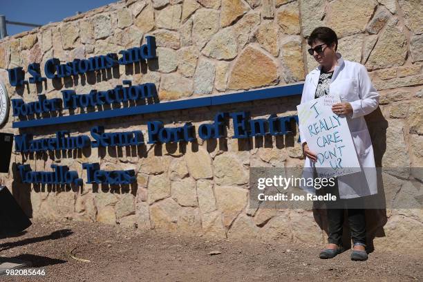 Dr. Gillian Harris holds a sign that reads, 'I really care, don't U? ' as she joins with other health care professionals to protest outside the tent...