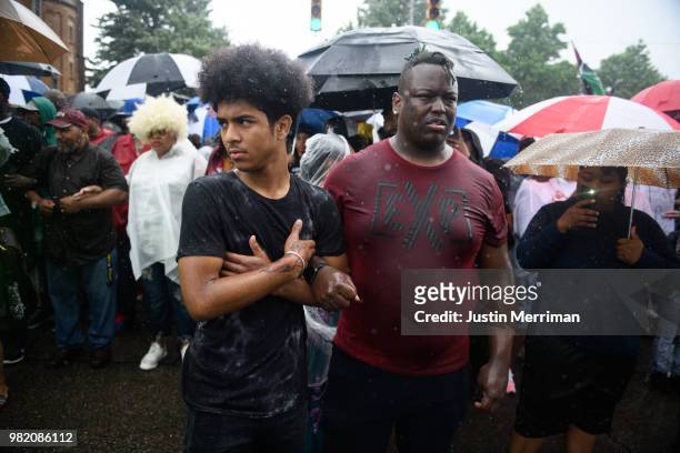 Men stand in the pouring rain as they join a protest for the police shooting of Rose during a Juneteenth celebration on June 23, 2018 in Pittsburgh,...