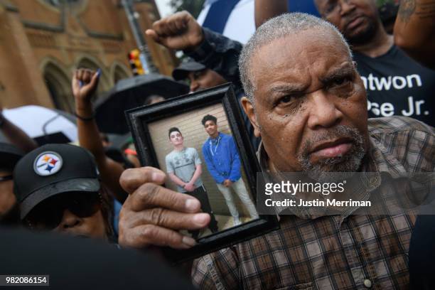 Man holds a photo of Antwon Rose as he joins a protest for the police shooting of Rose during a Juneteenth celebration on June 23, 2018 in...