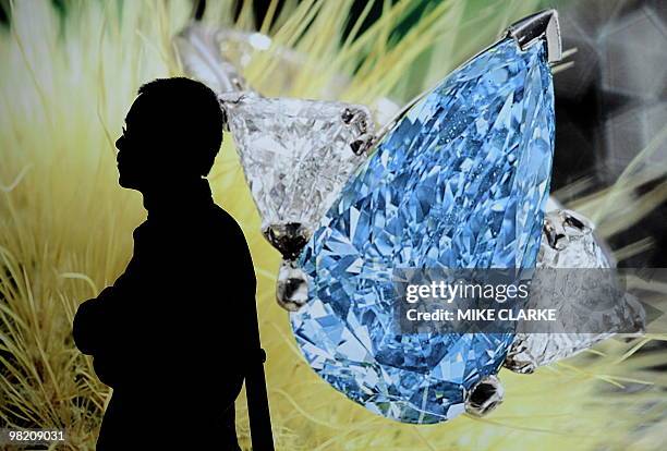 Man stands next to a photograph of a Millenium Blue Diamond, with a value of an estimated 4.6 to 5.9 million US dollars during a Sotheby's press...