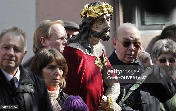 Believers stand next to a statue depicting Jesus during the Good Friday procession to commemorate the death of Christ on April 2, 2010 in Lohr,...