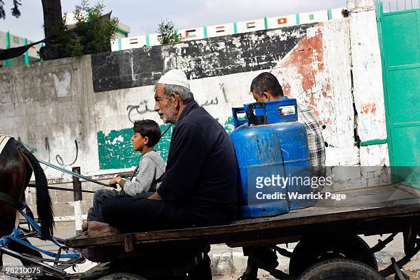 Palestinians carry gas canisters on the back of their horse-drawn cart on March 25 in Shujayia, Gaza Strip. Nearly all goods for sale in Gaza have...