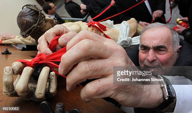 Members of the town's crafts guilds decorate a baroque sculpture Christ hanging on the cross during a Good Friday procession on April 2, 2010 in Lohr...
