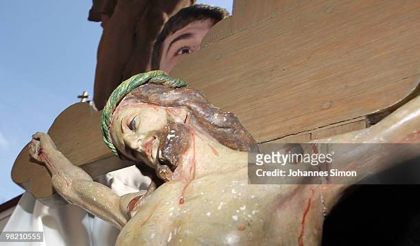 Little boy peers over a wooden depiction of Jesus on the cross during a Good Friday procession on April 2, 2010 in Lohr am Main, Germany. Several...