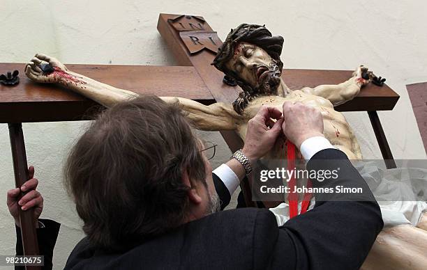 Members of the town's crafts guilds decorate a baroque sculpture Christ hanging on the cross during a Good Friday procession on April 2, 2010 in Lohr...