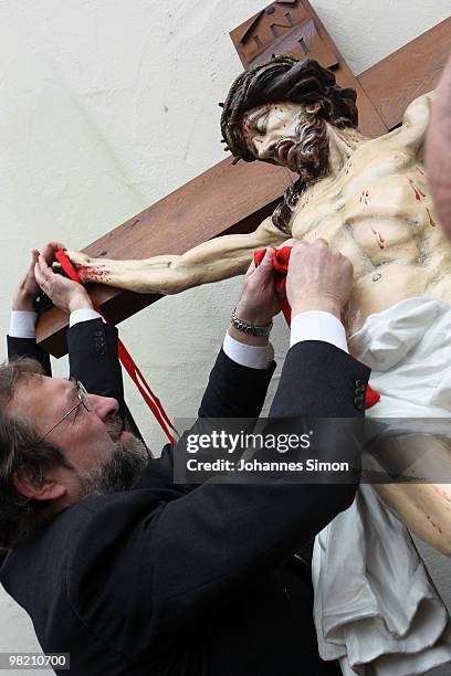 Members of the town's crafts guilds decorate a baroque sculpture Christ hanging on the cross during a Good Friday procession on April 2, 2010 in Lohr...