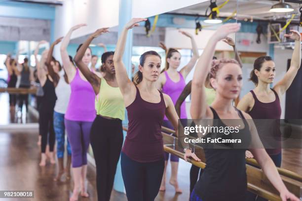 multiethnic group of women do a barre workout together in a modern health club - pike position stock pictures, royalty-free photos & images