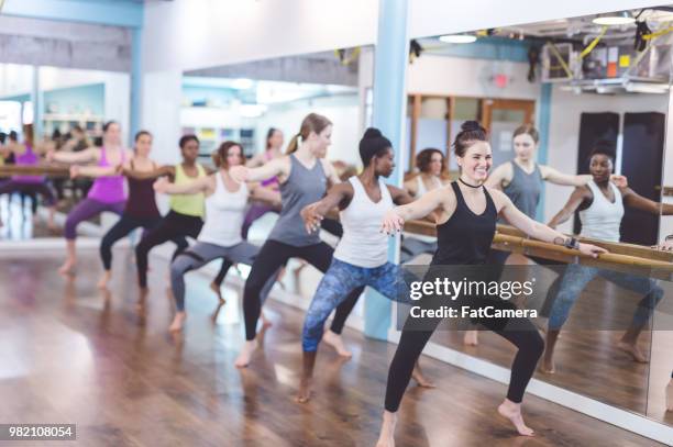 multiethnic group of women do a barre workout together in a modern health club - pike position stock pictures, royalty-free photos & images